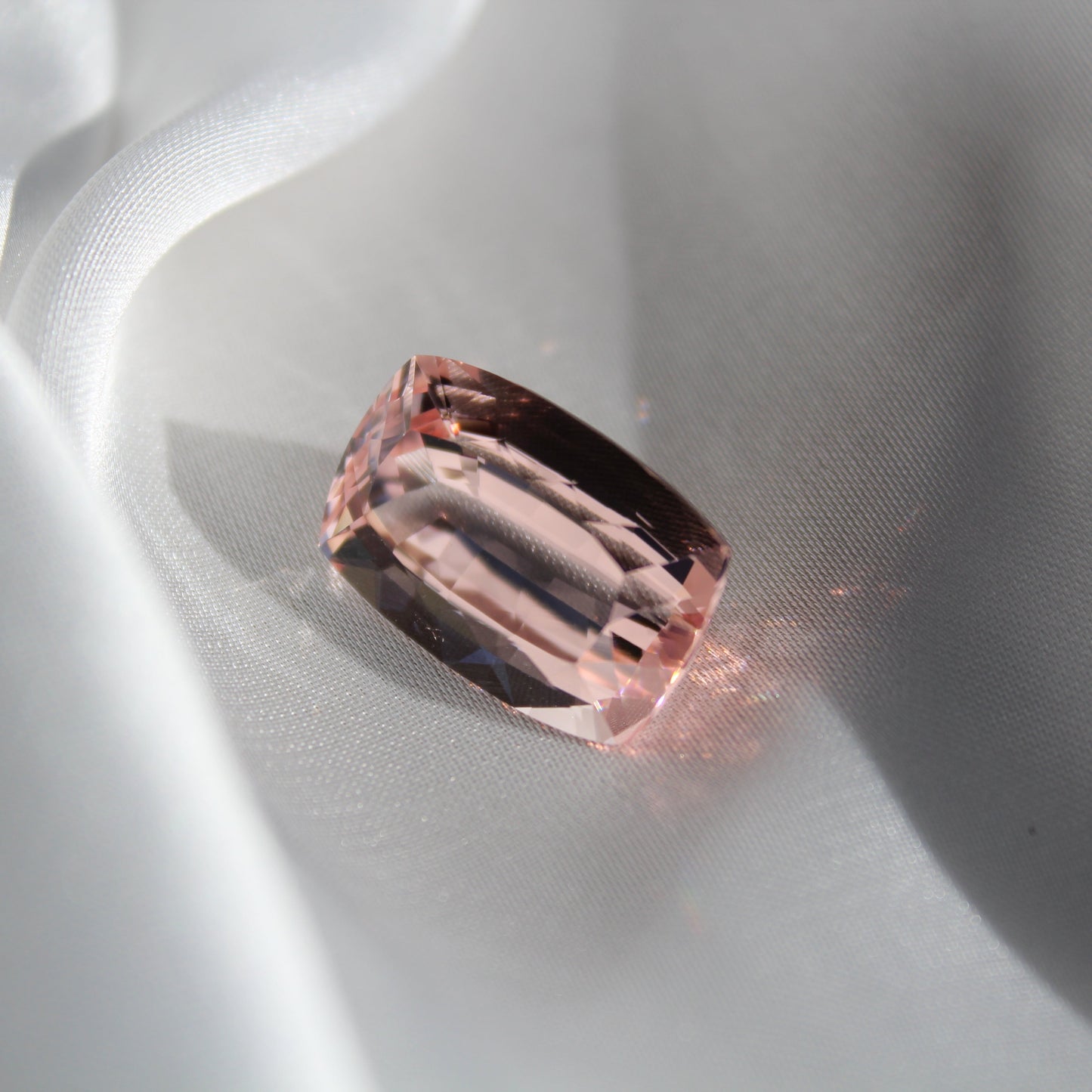 Pink gemstone on a white silk background