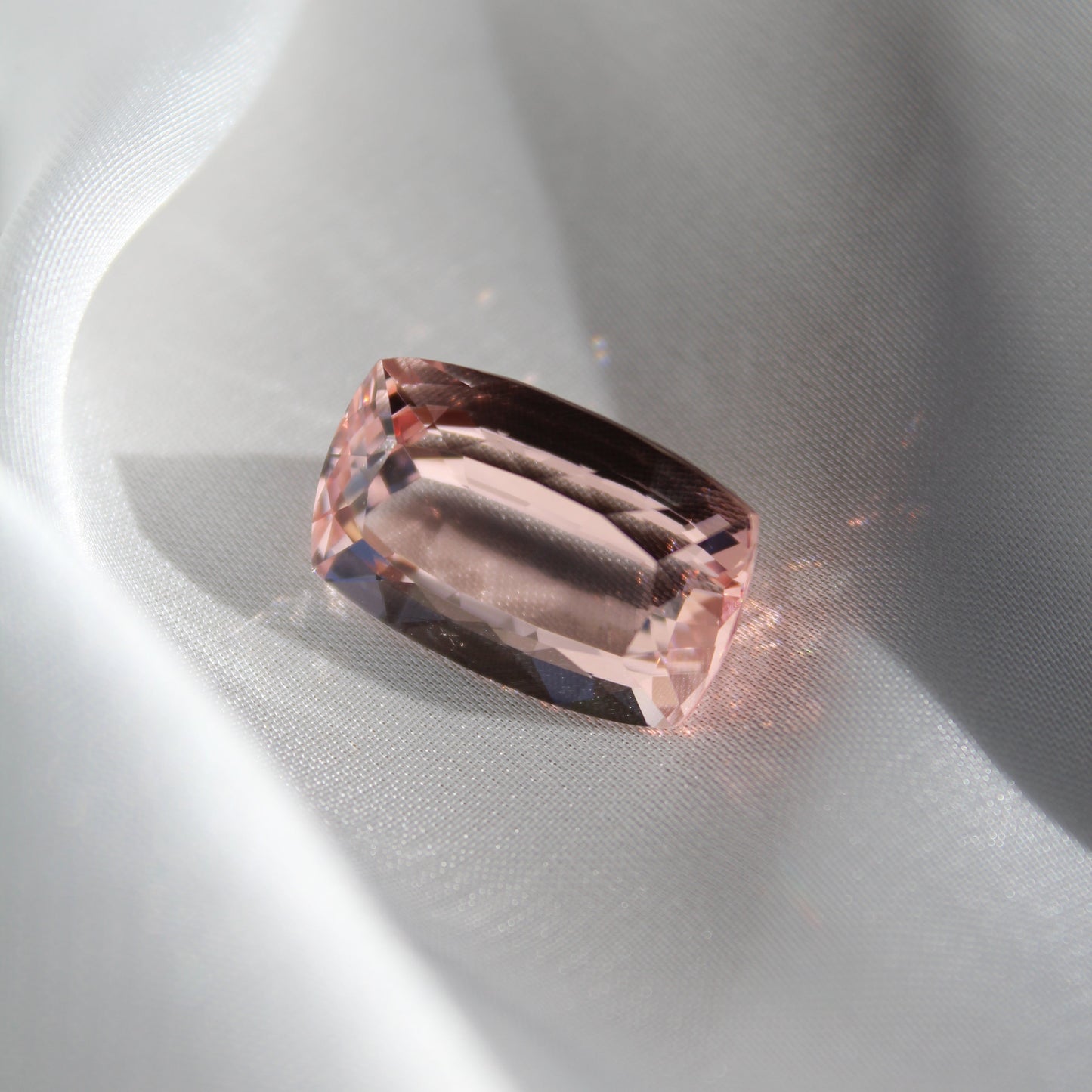 Close-up of a pink gemstone on a white silk background
