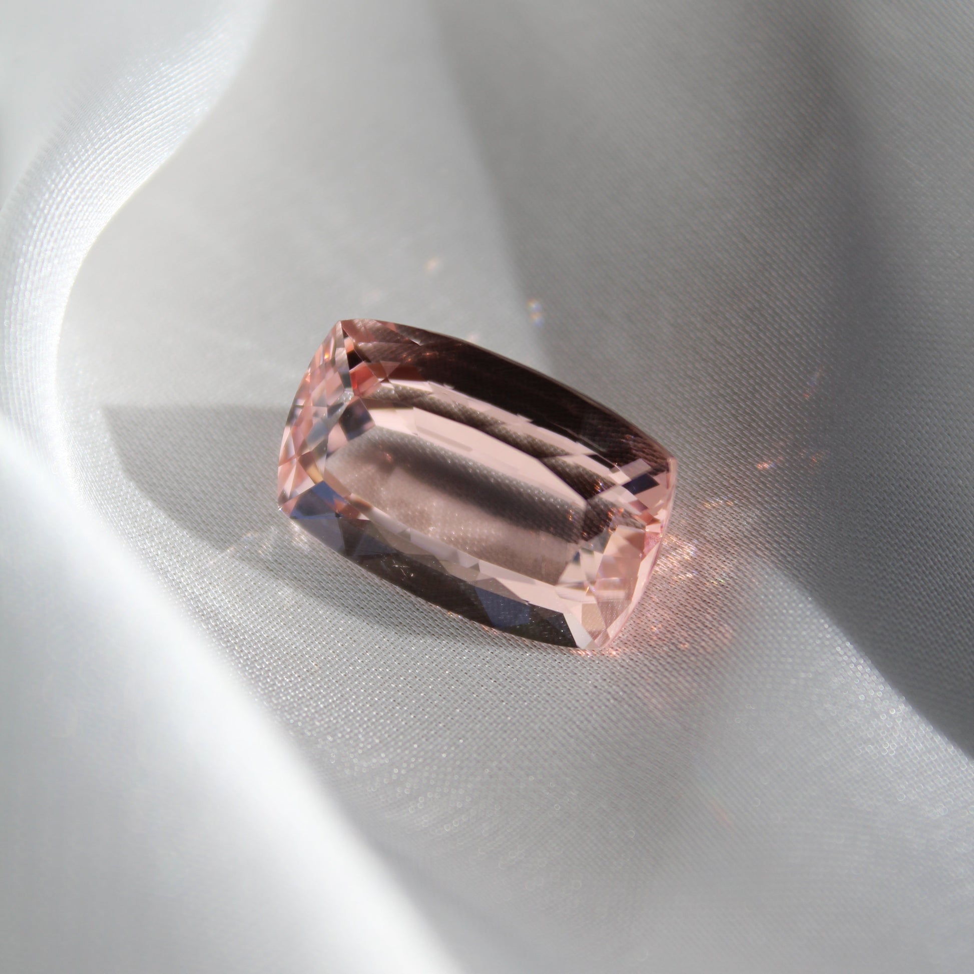 Close-up of a pink gemstone on a white silk background