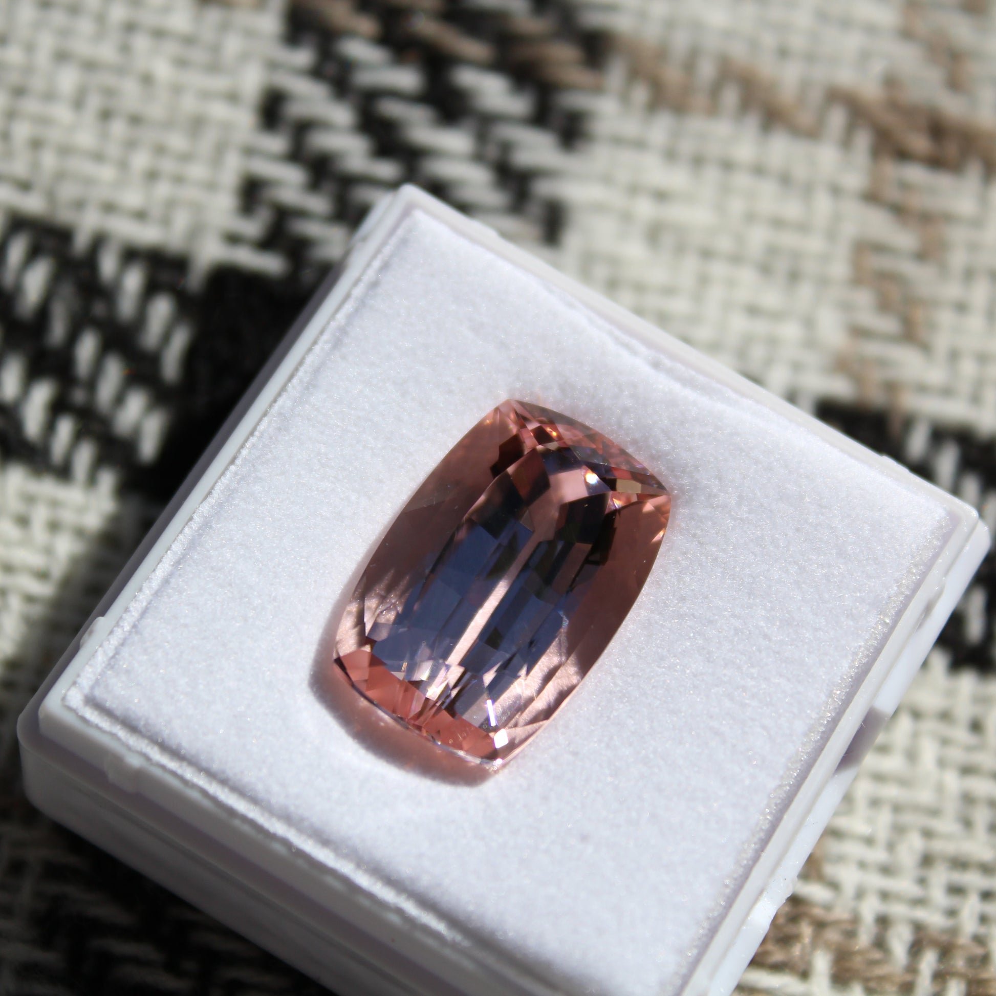 Pink gemstone on a white cushion with a textured fabric background