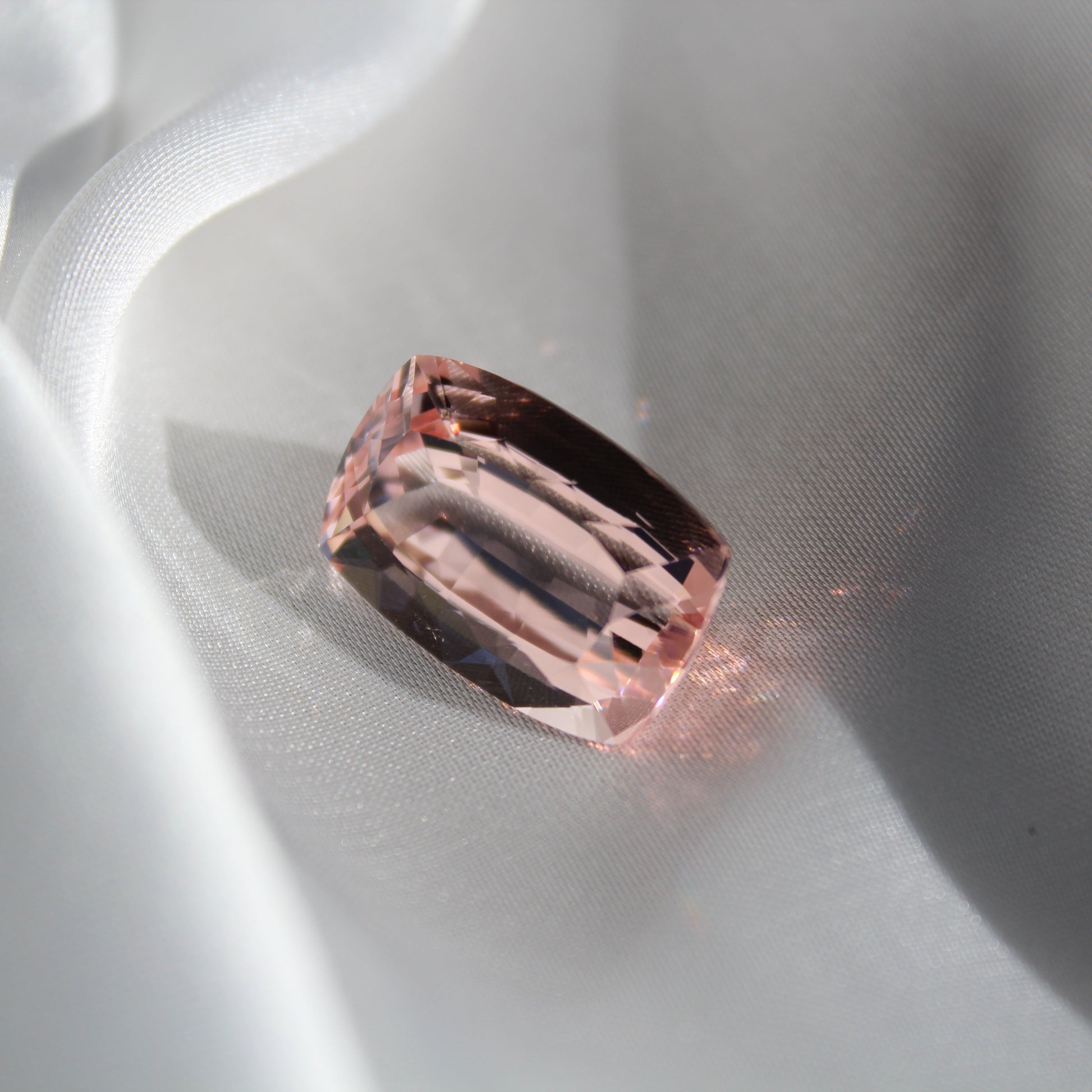 Pink gemstone on a white silk background