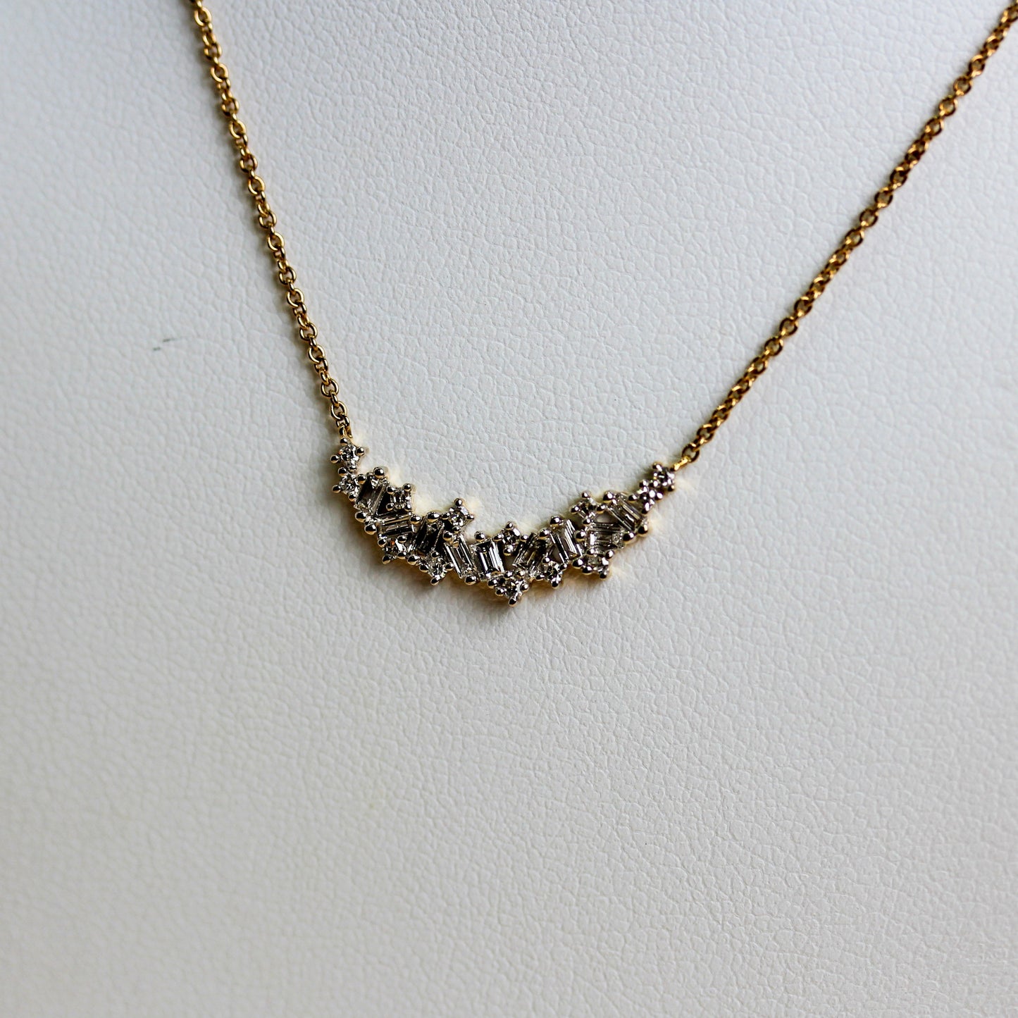Close-up of mixed-cut diamond curved bar in 9ct gold showing baguette and round brilliant claw settings — Jon Crosbie Jeweller