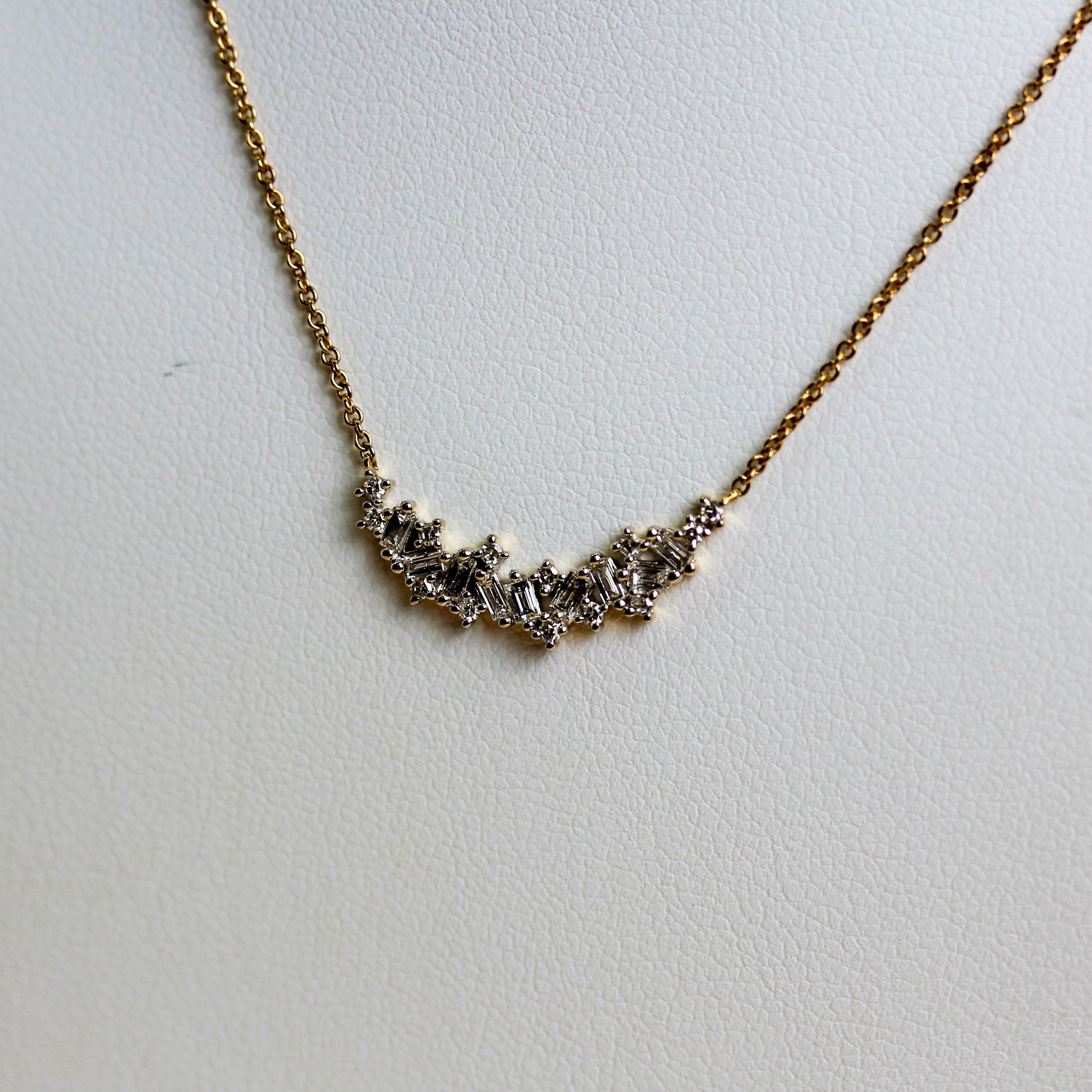 Close-up of mixed-cut diamond curved bar in 9ct gold showing baguette and round brilliant claw settings — Jon Crosbie Jeweller