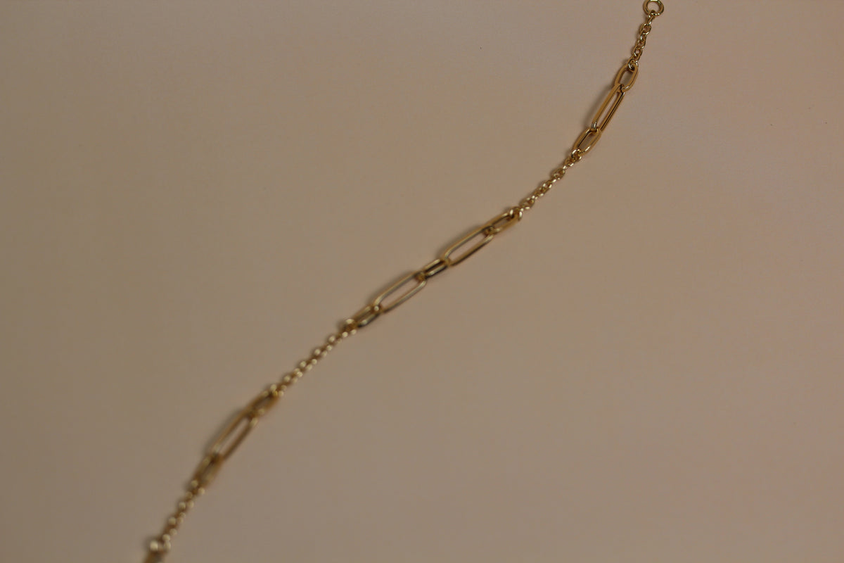 A close-up of a gold paperclip chain bracelet 