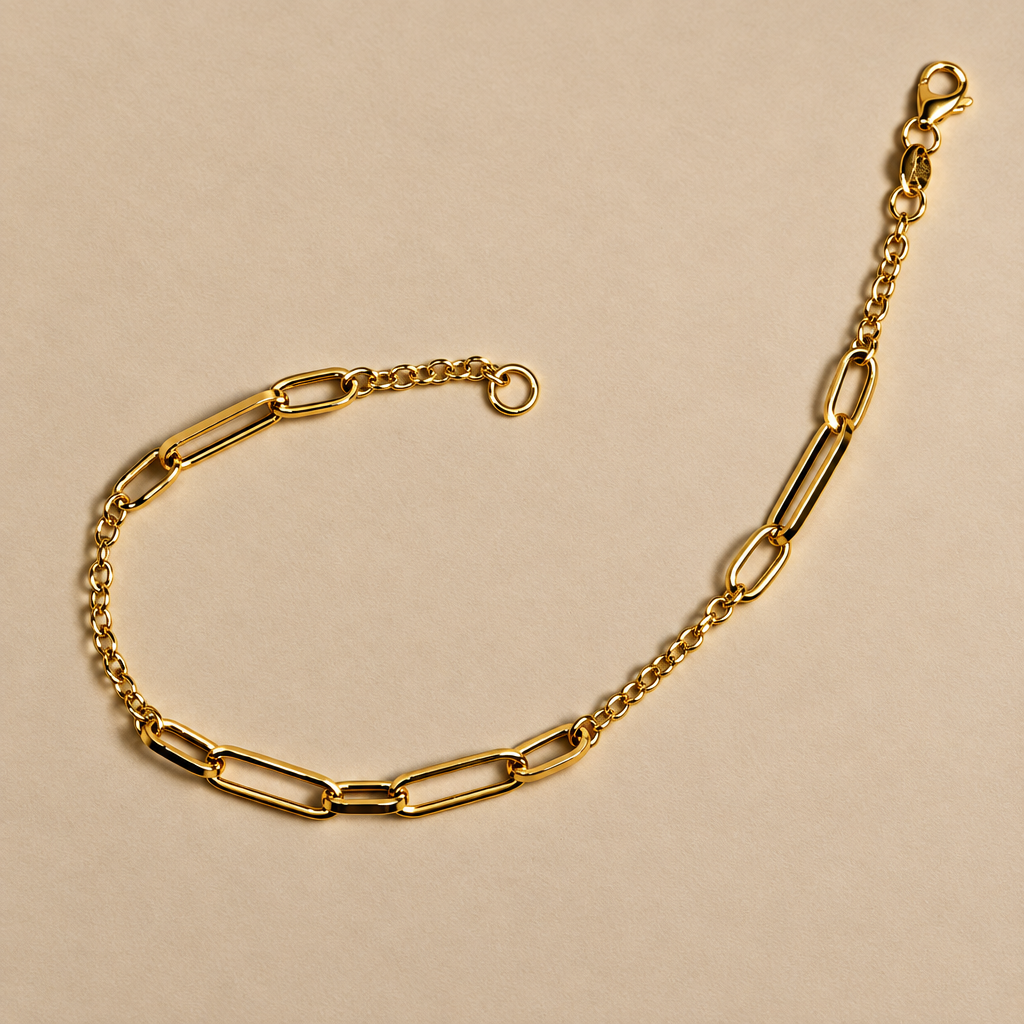 A gold paperclip chain bracelet with a lobster clasp, displayed on a plain beige background.