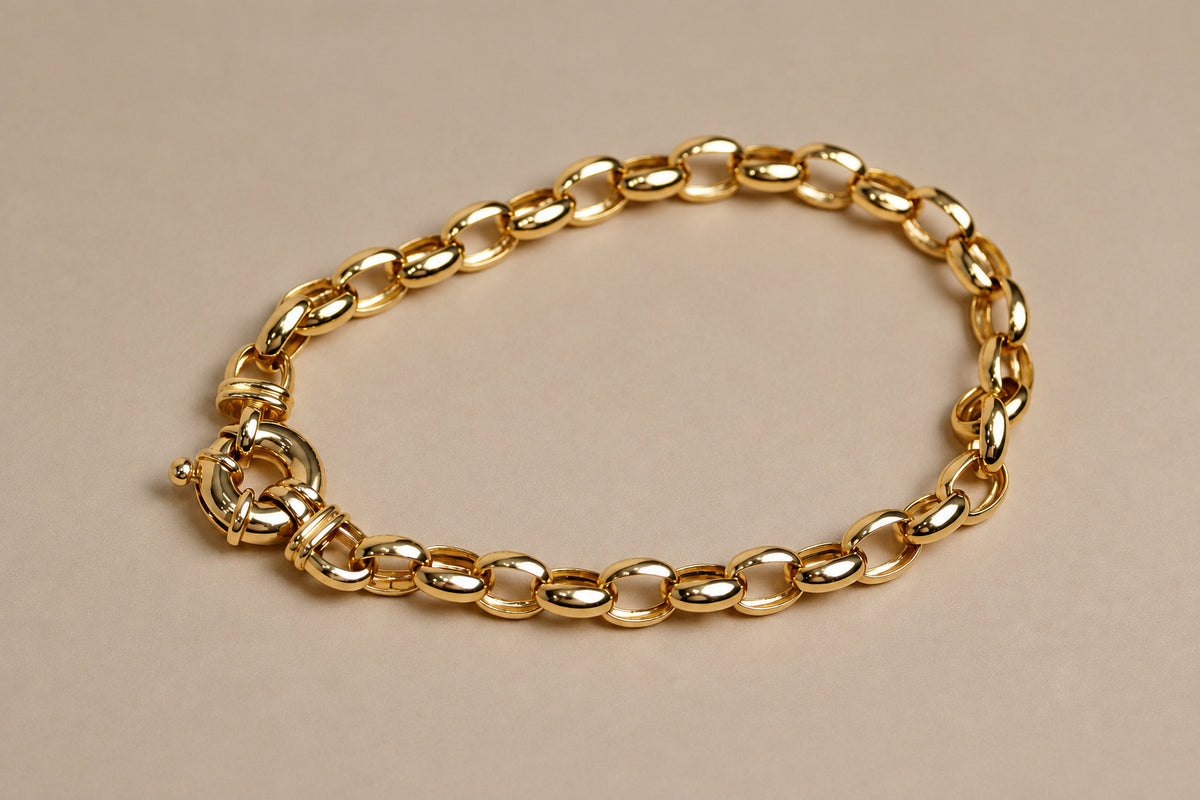 A gold belcher chain bracelet with a sailor clasp, displayed on a plain beige background.