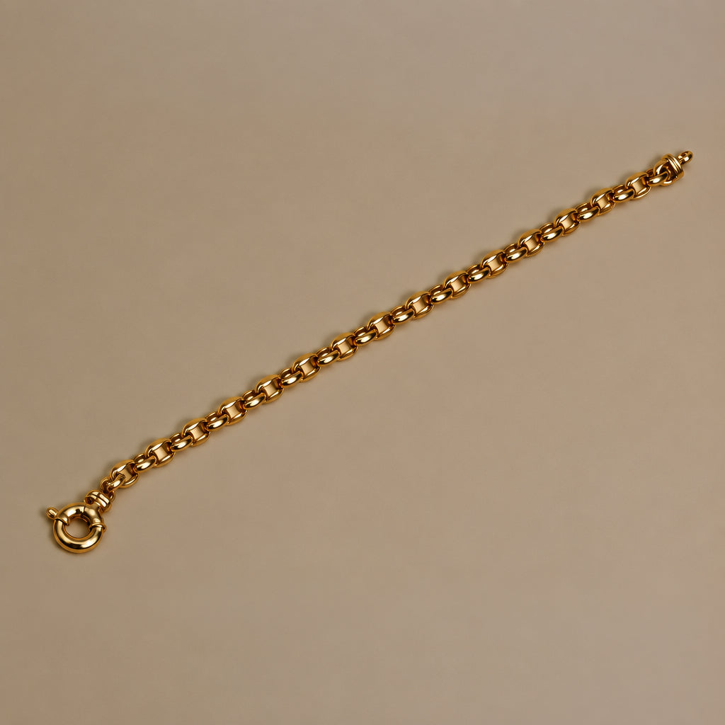 A gold belcher chain bracelet with a sailor clasp, displayed on a plain beige background.